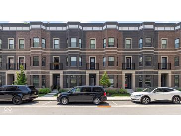 Charming brick townhomes featuring front patios and well-manicured landscaping add curb appeal at 127 Monon Green Blvd, Carmel, IN 46032