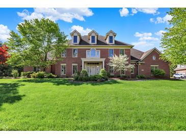 Beautiful two-story brick home with lush green lawn and mature trees on a sunny day at 13827 Driftwood Dr, Carmel, IN 46033