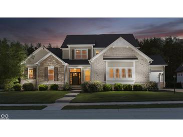 Beautiful two-story home with a stone and brick facade, manicured lawn, and professional landscaping at twilight at 14003 Grannan Ln, Carmel, IN 46074