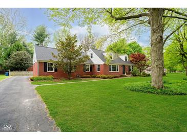 Charming brick home featuring manicured lawn, mature trees, black shutters, and dormer windows at 1409 Alimingo Dr, Indianapolis, IN 46260