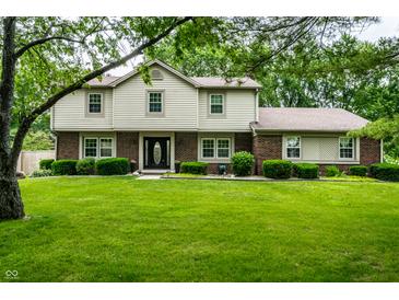 Traditional two-story home boasts a lush green lawn, mature trees and manicured bushes at 15203 Shoreway Ct, Carmel, IN 46032