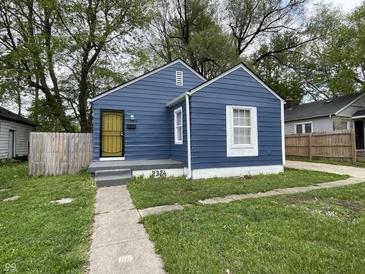 Charming blue bungalow with a yellow security door and well-maintained lawn at 2324 E 36Th St, Indianapolis, IN 46218