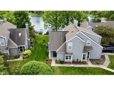 Charming grey two-story home with lush green lawn and serene lake view provides an inviting retreat at 2829 Somerset Bay, Indianapolis, IN 46240