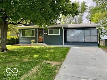 Charming single-story home featuring a well-manicured lawn and enclosed sunroom at 706 Alexander St, Greenwood, IN 46143