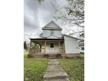 Two-story home featuring a covered front porch and light colored siding at 715 S Anderson St, Elwood, IN 46036
