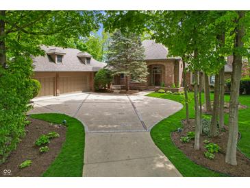 Stately brick home featuring a circle driveway, manicured landscaping, and an attached three-car garage at 7400 Oakbay Dr, Noblesville, IN 46062