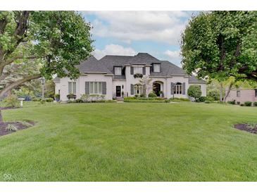 Stunning white home with lush green lawn, mature trees, and manicured landscaping creates idyllic curb appeal at 11508 Willow Ridge Dr, Zionsville, IN 46077