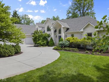 Charming brick home featuring a circular driveway, manicured lawn, and lush landscaping at 13909 Springmill Rd, Carmel, IN 46032