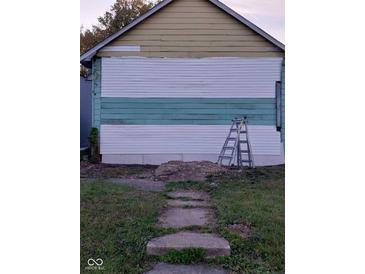 Shows the partially renovated exterior featuring horizontal siding, concrete block foundation, and an A-frame roof at 2134 Dr Andrew J Brown Ave, Indianapolis, IN 46202