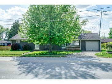 Charming home boasts mature trees, neutral siding, a front porch, and a convenient attached garage at 506 S Green St, Brownsburg, IN 46112