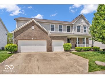 Beautiful two-story home featuring a brick facade, attached two-car garage, manicured lawn and charming front porch at 9712 Brooks Dr, McCordsville, IN 46055