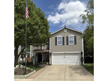 Charming two-story home featuring neutral siding, black shutters, and a well-maintained front yard with mature trees at 98 Frostwood Ln, Greenwood, IN 46143