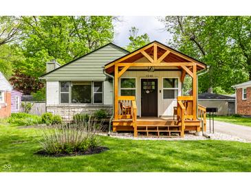 Charming home with a gabled facade, a wooden porch, and a well-manicured lawn at 1240 E 56Th St, Indianapolis, IN 46220