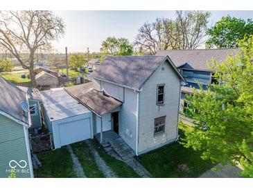Two-story home featuring a gray exterior, metal roofed garage, and mature trees at 2221 Station St, Indianapolis, IN 46218