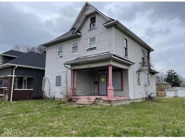 Two story home with covered porch, showing peeling paint and overgrown yard at 1014 W 33Rd St, Indianapolis, IN 46208