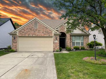 Charming single-story brick home featuring a two-car garage, manicured lawn, and beautiful landscaping at 10305 Lakeland Dr, Fishers, IN 46037