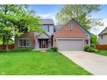 Charming two-story home featuring a well-manicured lawn, brick accents, and an attached two car garage at 10310 Foxwood W Dr, Carmel, IN 46280