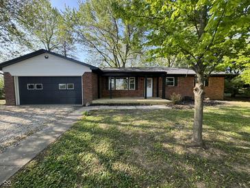 Charming brick ranch-style home with an attached garage and a cozy front porch, all surrounded by mature trees at 1725 E 100 S, Lebanon, IN 46052