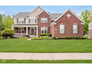 Charming two-story brick home featuring a welcoming front porch and lush green lawn at 3743 Earhart Dr, Carmel, IN 46074