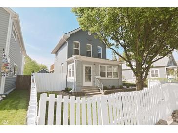 Charming two-story home featuring a brick foundation, inviting front porch, and a lovely white picket fence at 701 Lincoln St, Indianapolis, IN 46203