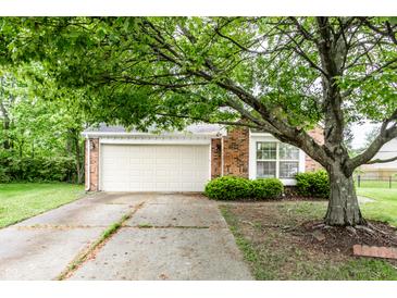 Charming brick home featuring a two-car garage and mature landscaping and healthy shade tree at 7703 Park North Lake Dr, Indianapolis, IN 46260