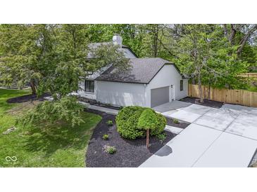 Side view of home featuring a two-car garage, mulch beds, and fresh concrete at 16 Maplecrest Dr, Carmel, IN 46033