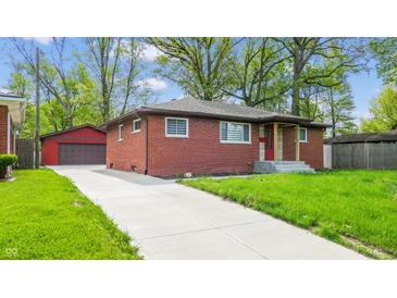 Charming brick home with a well-manicured lawn and a long driveway leading to a detached garage at 4213 N Audubon Rd, Indianapolis, IN 46226