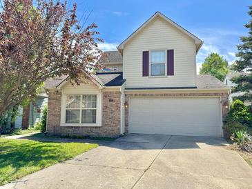 Charming two-story home featuring a brick facade, a two-car garage, and landscaped front yard, all under a clear blue sky at 4947 Peony Pl, Indianapolis, IN 46254