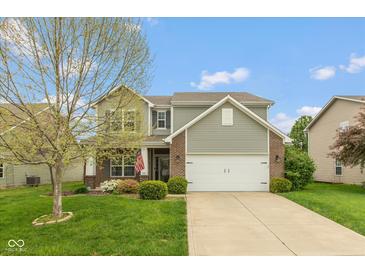 Charming two-story home featuring gray siding, a brick accent, a well-manicured lawn, and an attached two-car garage at 695 Bobtail Dr, Greenfield, IN 46140