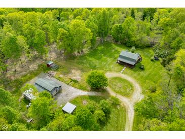 Stunning aerial view of a charming log cabin nestled on a beautiful lot surrounded by lush greenery and mature trees at 6968 S 300 W, Trafalgar, IN 46181