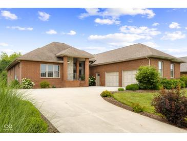 Inviting brick home featuring an attached two car garage and winding concrete driveway under a partly cloudy sky at 888 Westcreek Dr, Columbus, IN 47201