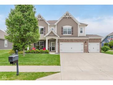Charming two-story home featuring a brick facade, three-car garage, manicured lawn, and lush landscaping at 15143 Gallop Ln, Fishers, IN 46040