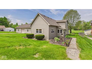 Charming home with light brown siding, landscaped yard, and a detached garage with an extra parking pad at 238 Jefferson St, Pendleton, IN 46064