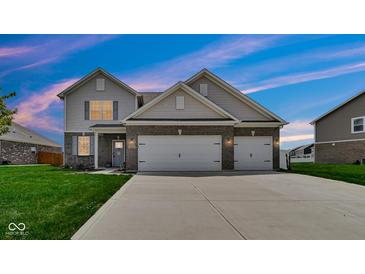 Two-story home featuring a two-car garage, neutral siding, brick accents and well-maintained lawn at 4763 W Tradwell Dr, New Palestine, IN 46163