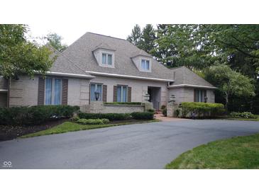 Charming brick home featuring dormer windows, manicured landscaping, and a paved driveway at 8065 Bayberry Ct, Indianapolis, IN 46250