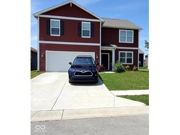 Two-story red house featuring an attached garage, well-maintained lawn, and a long driveway at 11204 Sashing Way, Monrovia, IN 46157