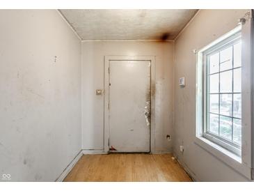 A view of the entryway, with a door, a window, and peeling paint on the walls at 2114 Sugar Grove Ave, Indianapolis, IN 46202