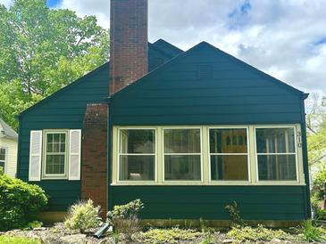 Charming home with a brick chimney, a yellow front door, and meticulously landscaped front yard at 310 S Butler Ave, Indianapolis, IN 46219