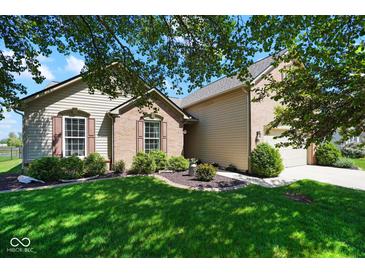 Charming home featuring a well-manicured front yard with lush green grass and beautiful landscaping at 5047 Skipping Stone Dr, Indianapolis, IN 46237