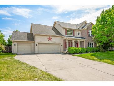 Charming two-story home featuring a three-car garage, red accents, and a well-maintained front lawn at 7023 Hartington Pl, Indianapolis, IN 46259