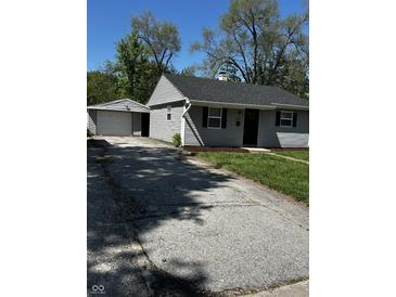 Quaint single-story home featuring gray siding, a dark roof, and a detached garage, offering cozy living at 7334 Westchester Dr, Indianapolis, IN 46226