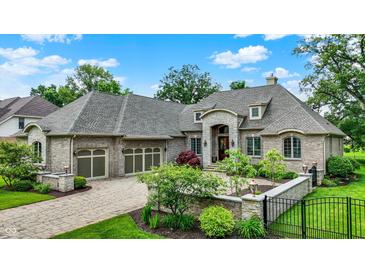 Stunning brick home featuring a stone entryway, lush landscaping, and an attached three-car garage at 8905 Stonebriar Dr, Indianapolis, IN 46259
