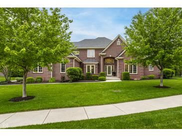 Beautiful brick home featuring a well-manicured lawn, mature trees, and inviting front entrance at 13309 Carmichael Ln, Carmel, IN 46074