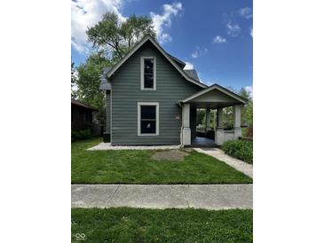 Charming two-story home with a covered front porch, green lawn, and mature trees at 44 S Butler Ave, Indianapolis, IN 46219