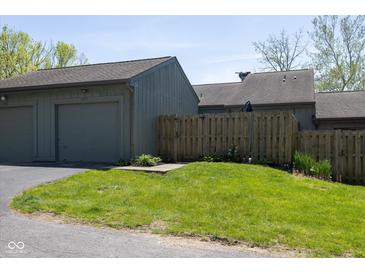 Attached garage and front yard featuring green grass and wooden fence at 5077 Vantage Point Rd # 1 Wm-5-1, Avon, IN 46123