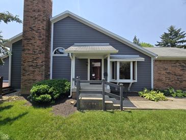 Charming home featuring a brick chimney and inviting front entrance with a manicured lawn at 8055 Foxchase Dr, Indianapolis, IN 46256