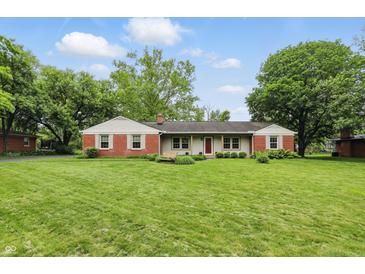 Charming single-story home with a manicured lawn and a combination of brick and light-colored siding at 5129 E 69Th St, Indianapolis, IN 46220