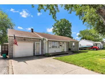 Charming home with an attached garage, an American flag, and a well-manicured lawn under a clear, blue sky at 518 N Carr Rd, Plainfield, IN 46168