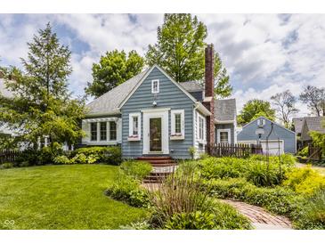 Charming blue bungalow with a brick chimney, garden landscaping, and walkway leading to the front entrance at 5219 N New Jersey St, Indianapolis, IN 46220