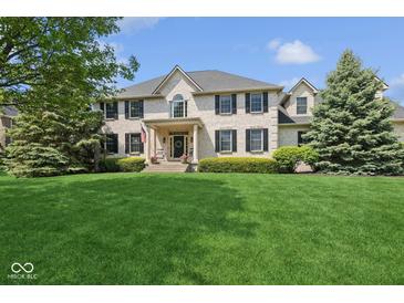 Stately two-story home featuring a well-manicured lawn and a classic brick facade with black shutters at 13868 Broad Mdw, Carmel, IN 46032